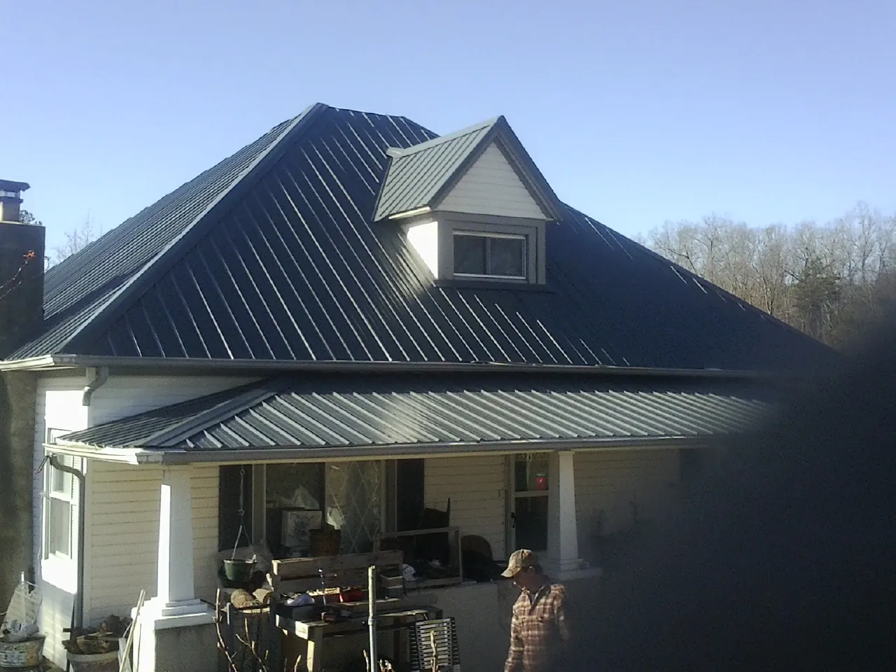 Dark blue standing seam metal roof with a dormer above a front porch in New Cumberland