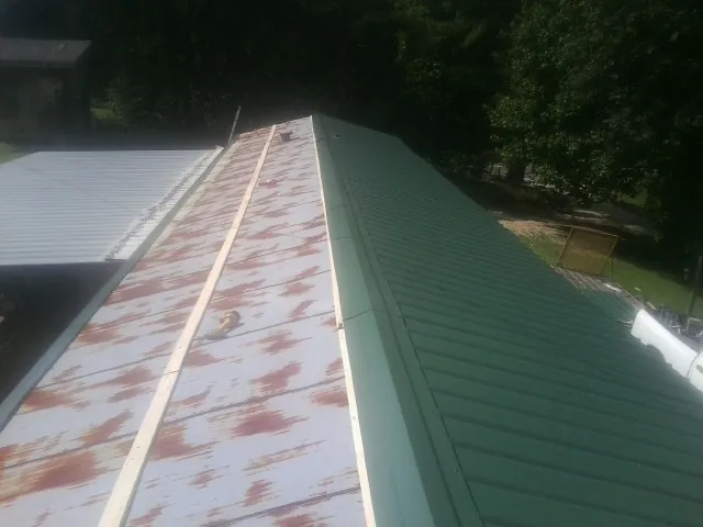 Old rusted panels beside newly installed green metal roofing — Wind Damage Roof Repair by Roofing Brothers in New Cumberland