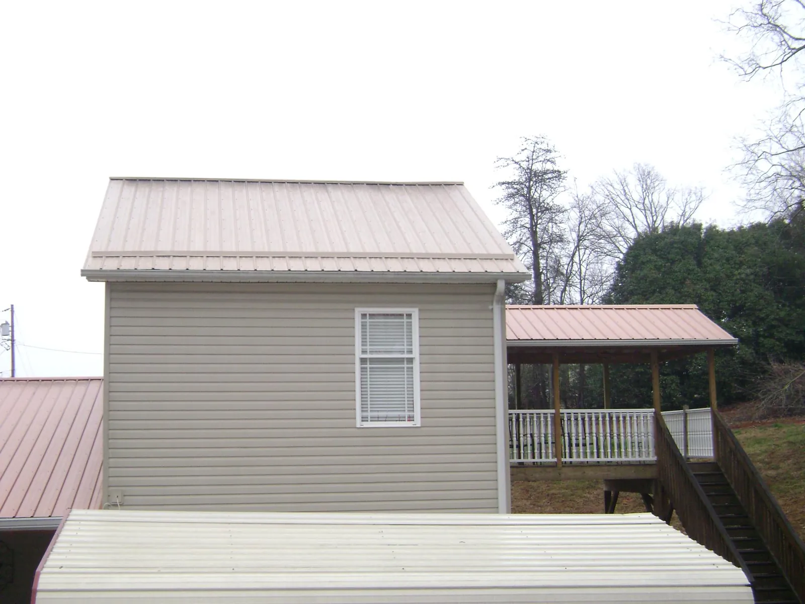 Tan metal roofs on a two story addition and attached porch, from a Roof Replacement job in New Cumberland